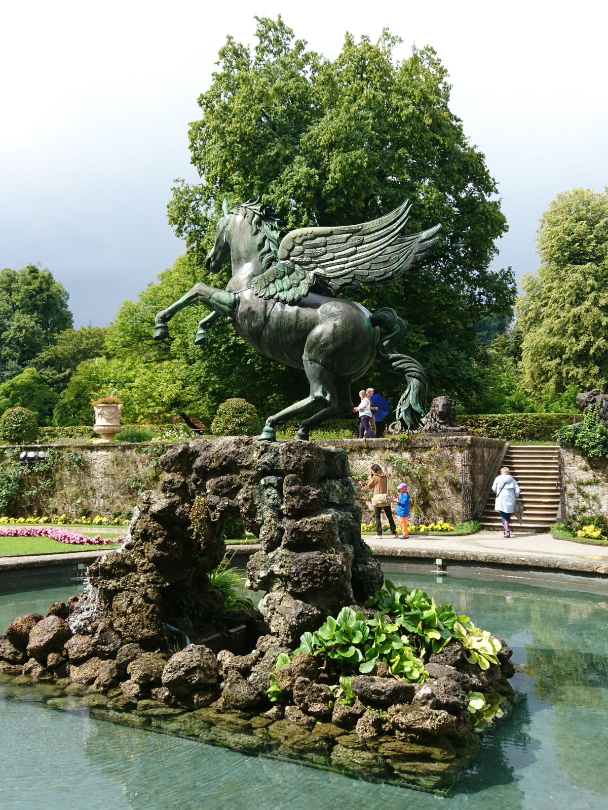 Die Pegasusgruppe im Mirabellgarten in Salzburg, dahinter die alten Bäume des Parks.